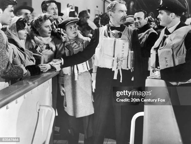 Clifton Webb holds Barbara Stanwyck's arm as he speaks to a ship's officer while Robert Wagner , Harper Carter and Audrey Dalton look on in a still...