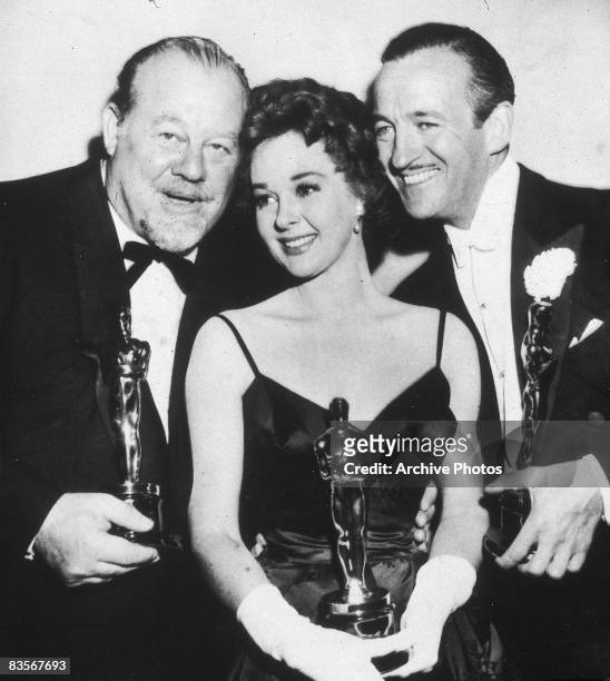 From left to right, American singer and actor Burl Ives , American actress Susan Hayward and British actor David Niven pose together holding their...