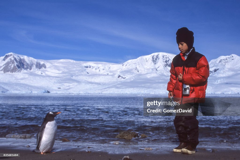 Garçon de la jeune Latino sur la plage de l’Antarctique à la recherche de sauvages manchot papou