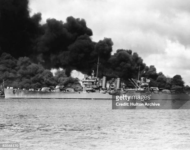 The American light cruiser USS Phoenix passing the burning USS West Virginia and USS Arizona, during the Japanese attack on Pearl Harbor, 7TH...