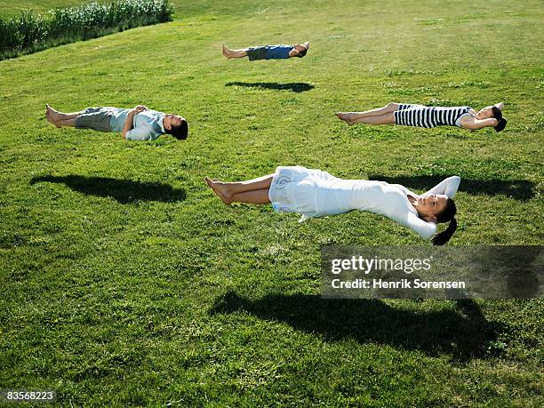 group of people realxing floating above the grass - levitation stock-fotos und bilder