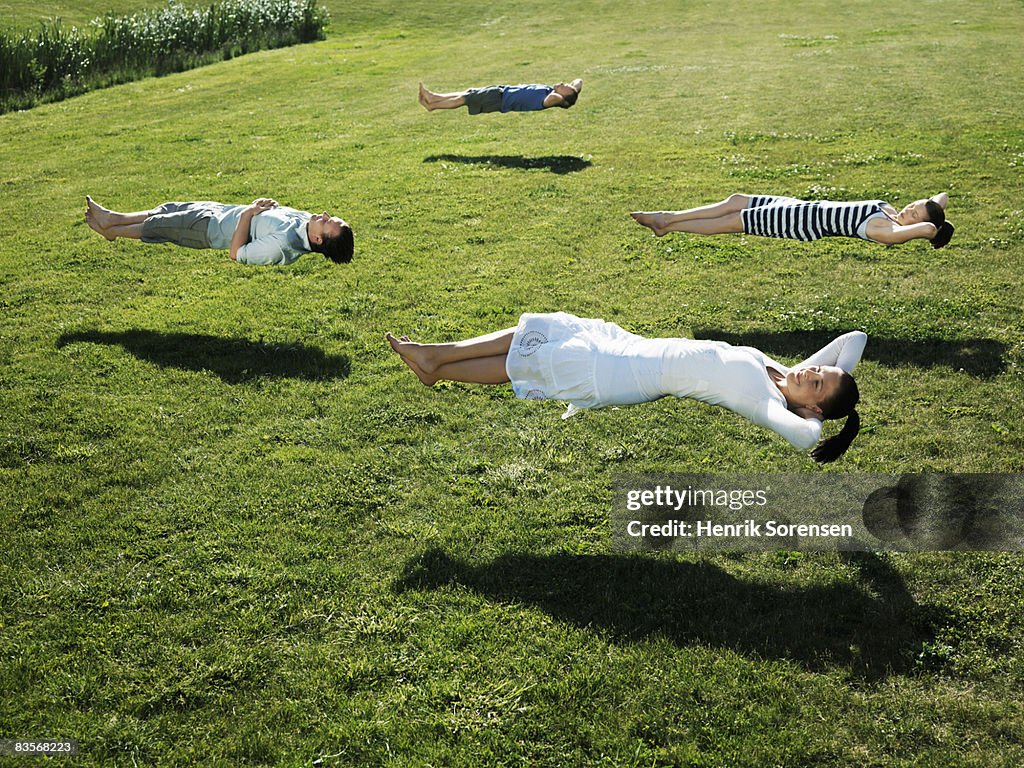 Group of people realxing floating above the grass