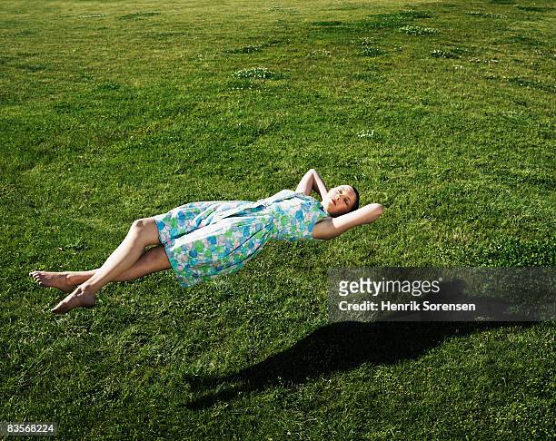 woman realxing floating above the grass - day dreaming stock pictures, royalty-free photos & images