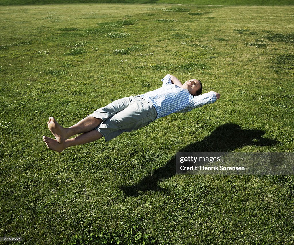 Man realxing floating above the grass