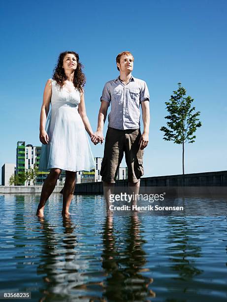couple standing on the water holding hands - ankle deep in water fotografías e imágenes de stock