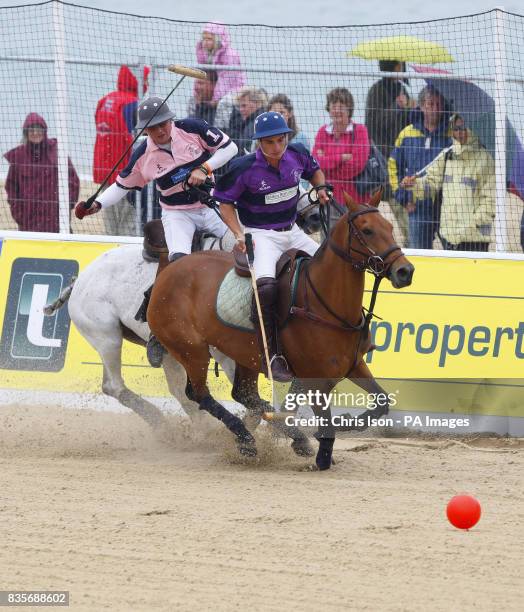 Sparse crowd watches the action during the British Beach Polo Championships from under raincoats and umbrellas at the exclusive Sandbanks area of...