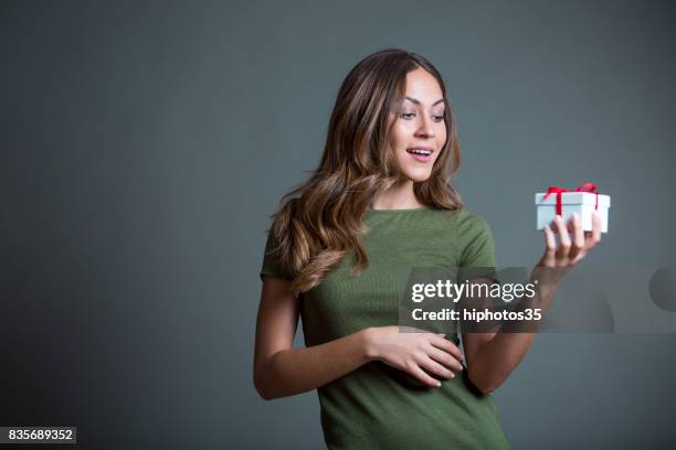 cute femme heureuse avec un cadeau enveloppé sur fond gris - avantage photos et images de collection