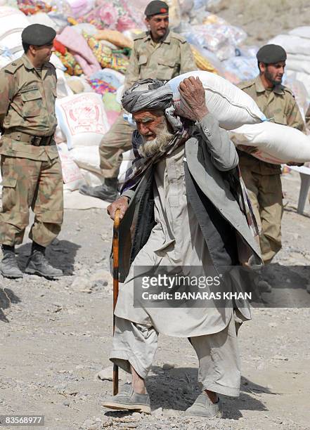 An elderly Pakistani earthquake survivor carries relief goods distribute by army at a hilly area of Wam, one of about eight sparsely populated...