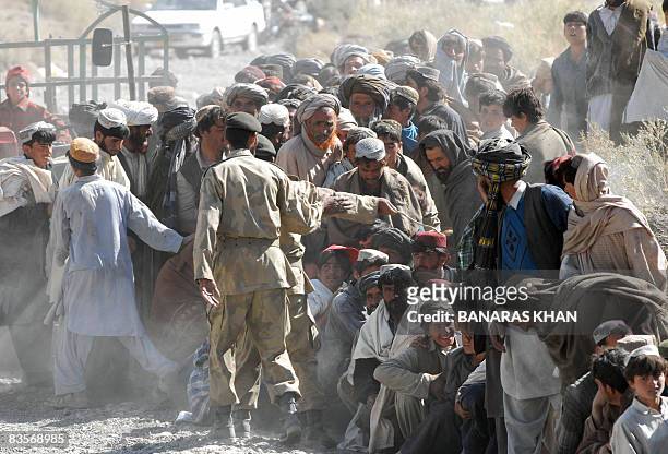 Pakistani earthquake survivors lineup as they wait for relief supplies at a hilly area of Wam, one of about eight sparsely populated villages...