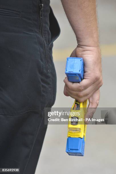 Police officer holds a Taser X26 fitted with blue training cartriges that don't deliver an electric shock