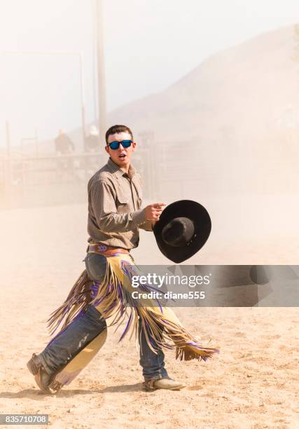 cowboy looks back at the crowd amid the dust after his ride - chaps stock pictures, royalty-free photos & images