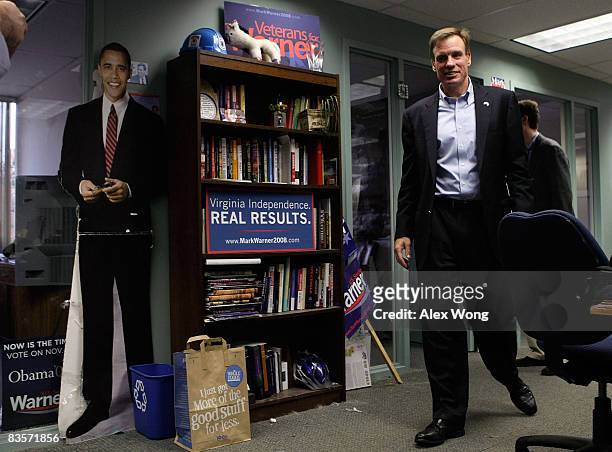 Sen.-elect Mark Warner passes by a paper cutout of U.S. President-elect Barack Obama at his campaign headquarters November 5, 2008 in Alexandria,...
