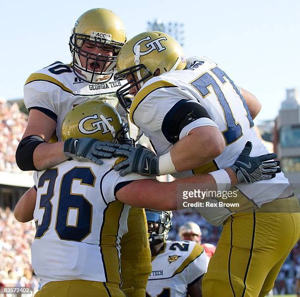 Lucas Cox of the Georgia Tech Yellow Jackets is congratulated by teammates Dan Voss and Joseph Gilbert after scoring a touchdown against the Florida...