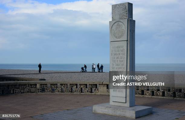 This photo taken on October 9, 2016 in Dieppe shows people standing on the beach near a memorial dedicated to Canadian soldiers during the WWII...