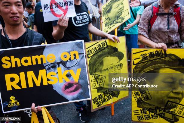 Protesters hold placards during a march in Hong Kong on August 20 to protest the jailing of Joshua Wong, Nathan Law and Alex Chow , the leaders of...