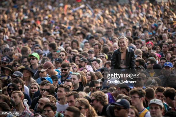 vrouw op iemands schouders in dikke concert menigte - concert crowd stockfoto's en -beelden