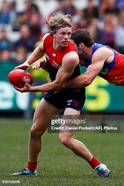 Jayden Hunt of the Demons handpasses the ball whilst being tackled by Michael Close of the Lions during the round 22 AFL match between the Melbourne...