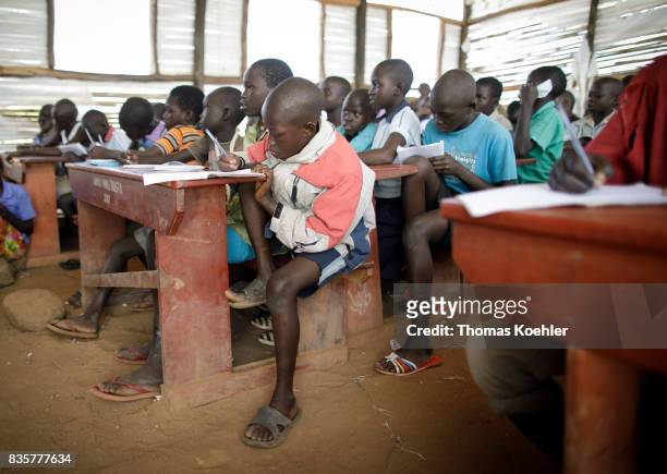 An Students are sitting at school camps in a school at Rhino Refugee Camp Settlement in northern Uganda. Here, children of local people and refugees...