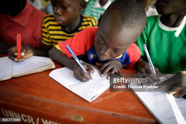 Students write in their school notebooks during the lesson. School at Rhino Refugee Camp Settlement in northern Uganda. Here, children of local...