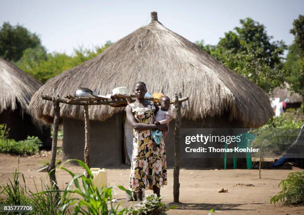 Rhino, Uganda A young woman stands with her toddler in front of a hut at the Rhino Refugee Camp Settlement in northern Uganda. The area is home to...