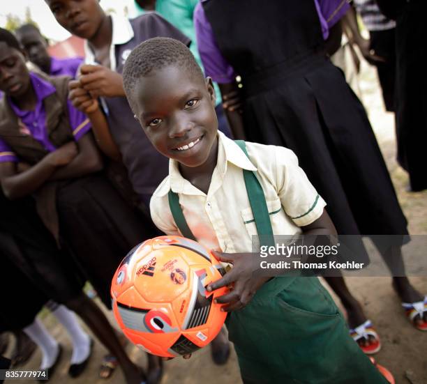 Student with a football in her hand in a school at the Rhino Refugee Camp Settlement in northern Uganda. Here, children of local people and refugees...