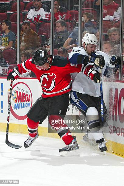 Zach Parise of the New Jersey Devils and Andrej Meszaros of the Tampa Bay Lighting play for the loose puck during along the boards during the third...