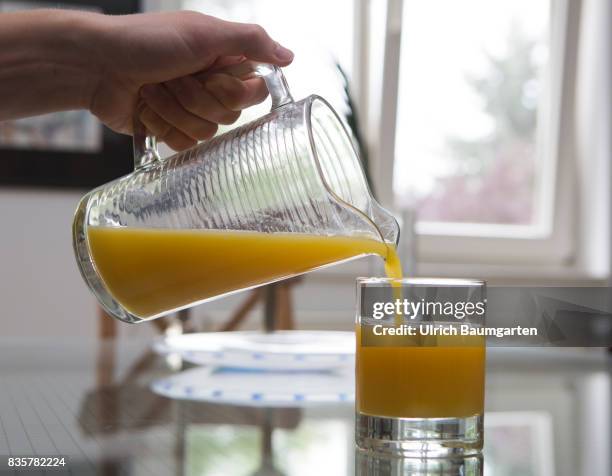 Vitamin C - Allroundgenie in terms of human health. The photo shows a hand with carafe during filling of orange juice into a glas.