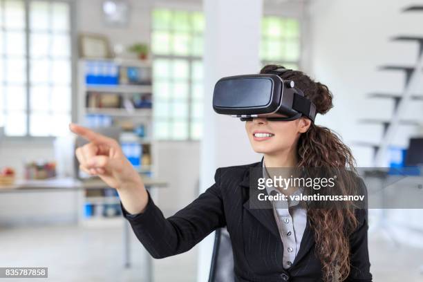 femme à l’aide de casque vr au travail - casques réalité virtuelle photos et images de collection