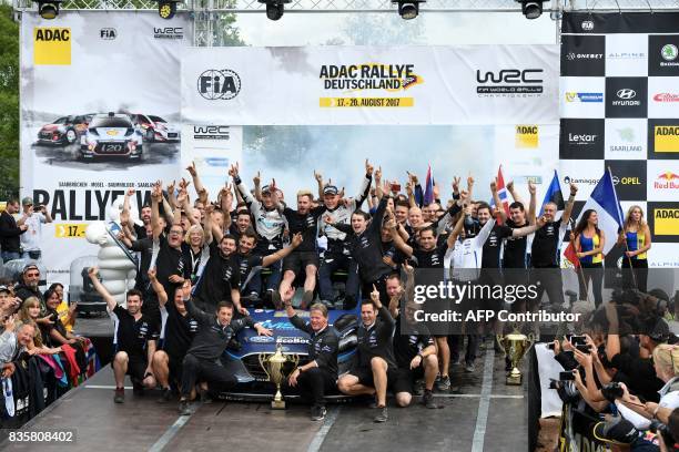 Ott Tanak of Estonia and his co- driver Martin Jarveoja of Estonia celebrate with their team after they finish at the first place in front of Andreas...