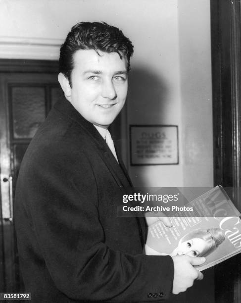 British actor Richard Dawson holds a copy of McCall's magazine in the waiting room of the clinic where his wife, actress Diana Dors, has just given...