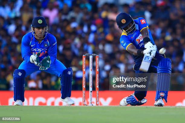 Sri Lankan cricketer Angelo Mathews plays a shot as India's MS Dhoni looks on during the 1st One Day International cricket match bewtween Sri Lanka...