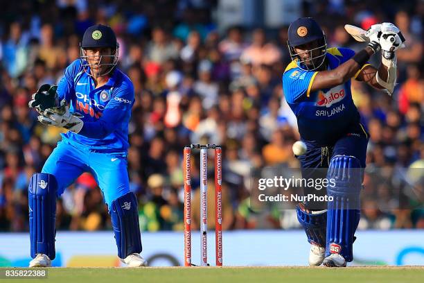 Sri Lankan cricketer Angelo Mathews plays a shot as India's MS Dhoni looks on during the 1st One Day International cricket match bewtween Sri Lanka...