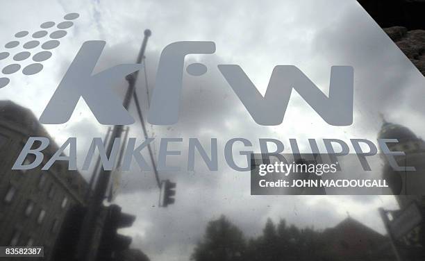 Picture taken on September 18, 2008 shows passers-by being reflected in a plaque bearing the logo of German state development bank KfW at the bank's...