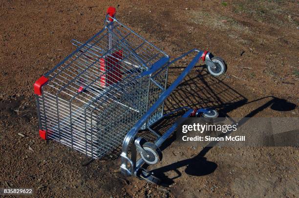 stolen and abandoned shopping trolley lies on its side in a paddock in canberra, australian territory, australia - abandoned cart stock pictures, royalty-free photos & images