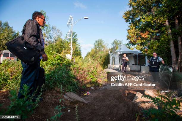 Officers speak with a man claiming to be from Eritrea as he prepares to cross the US/Canada border illegally near Hemmingford, Quebec, August 20,...