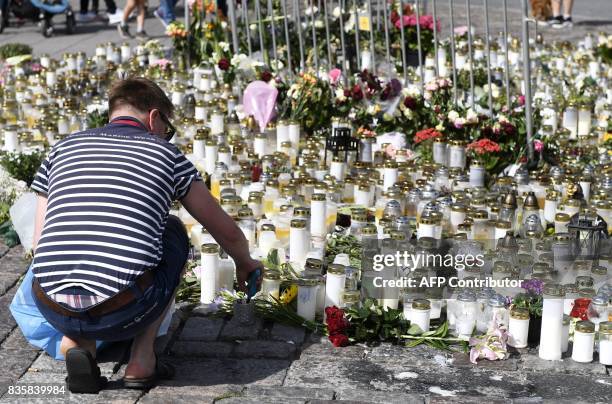 People bring candles and flowers to the makeshift memorial for the victims of the stabbings at the Turku Market Square, Finland on August 20, 2017....