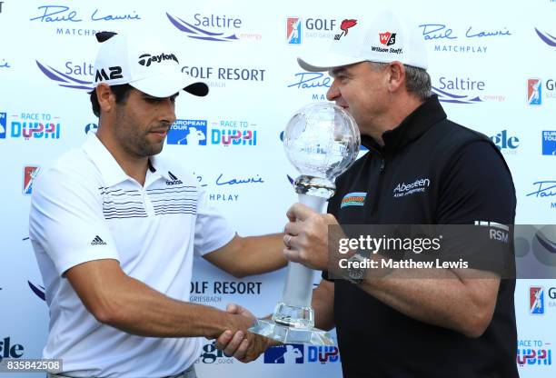 Adrian Otaegui of Spain receives the trophy from Paul Lawrie of Scotland following his victory over Marcel Siem of Germany during the final match of...