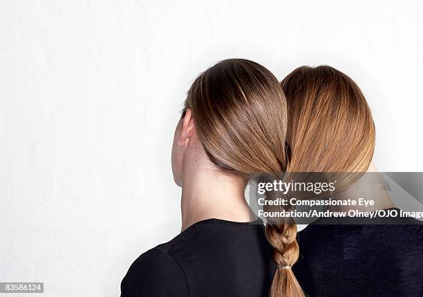 two women tied together by hair plait - zopf stock-fotos und bilder