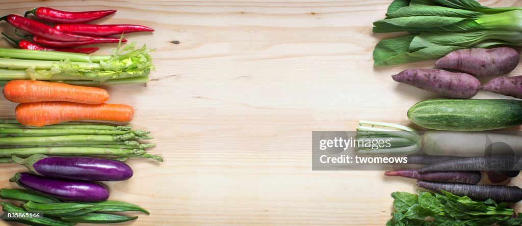 Flat lay various uncooked vegan border on wooden background.