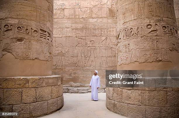 egyptian man standing in karnak temple columns - hieroglyphics stock-fotos und bilder