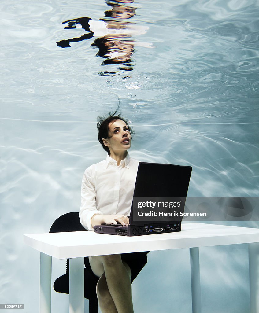 Woman working on her laptop under water