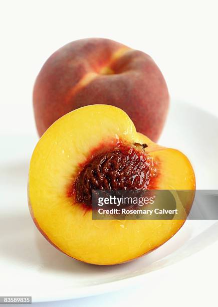 peach and half a peach cut to reveal the stone. - もも ストックフォトと画像