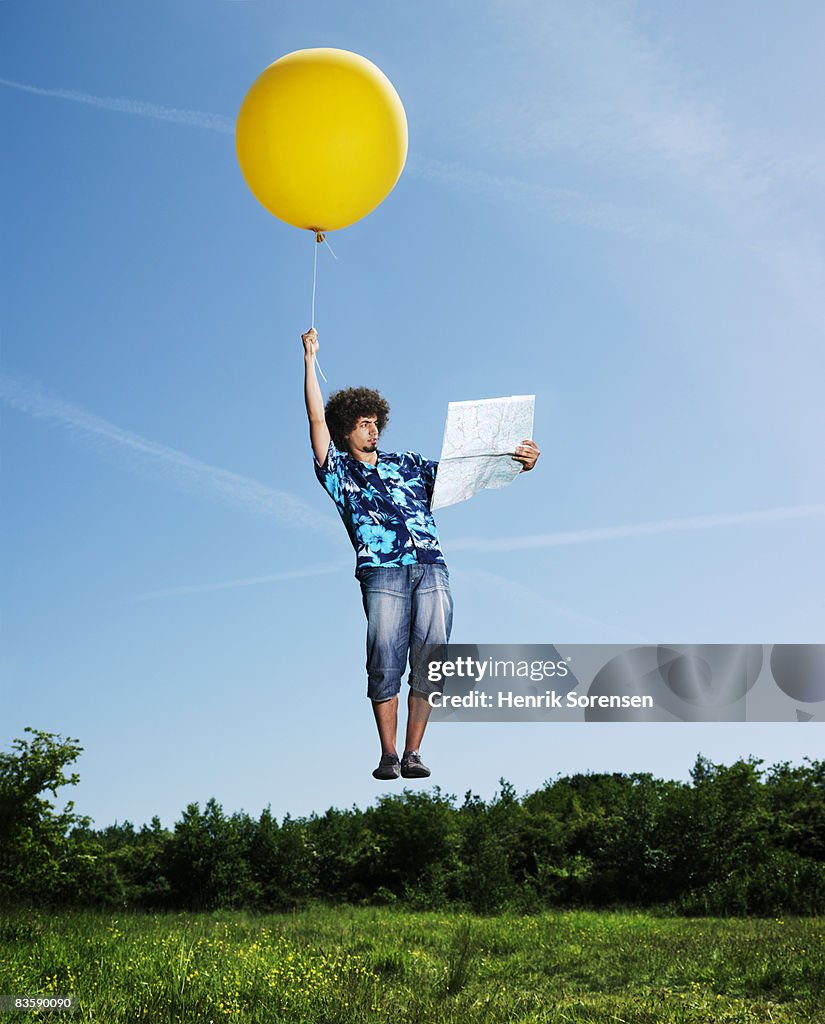 Man flying holding a big of Balloons watching a Ro