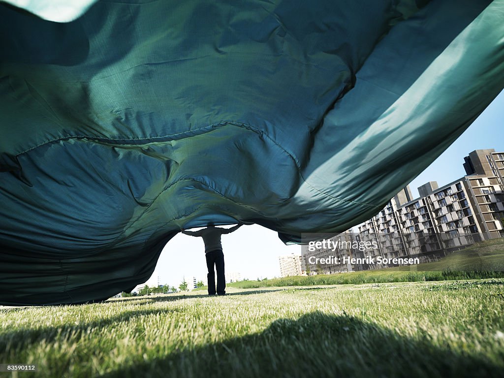 Man holding a big piece of cloth blowing in the wi