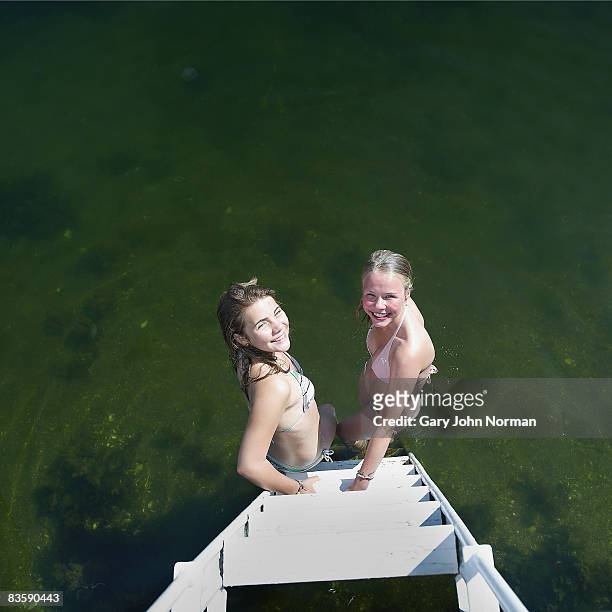 two girls at the steps of dock feet in water - ankle deep in water fotografías e imágenes de stock