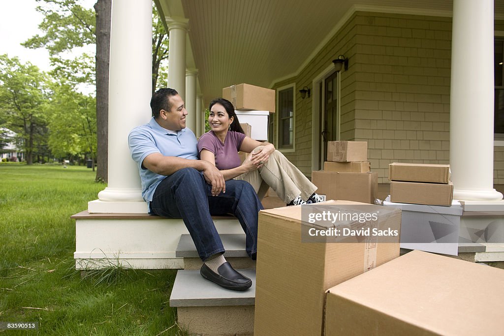 Happy couple with boxes, talking on porch
