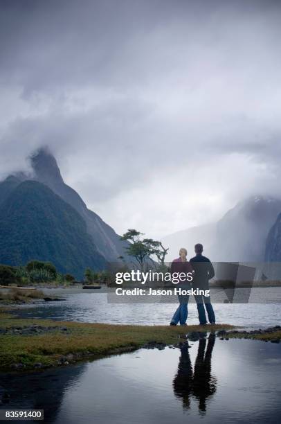 couple looking at dramatic, stormy mountain - sturm der liebe stock-fotos und bilder