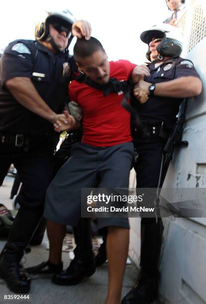 Police officers detain a man as hundreds of mostly peaceful supporters of same-sex marriage march for miles in protest against the Church of Jesus...