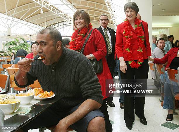 New Zealand's Labour Prime Minister Helen Clark greets supporters while a man eats his lunch as she tours a shopping centre in Auckland's western...