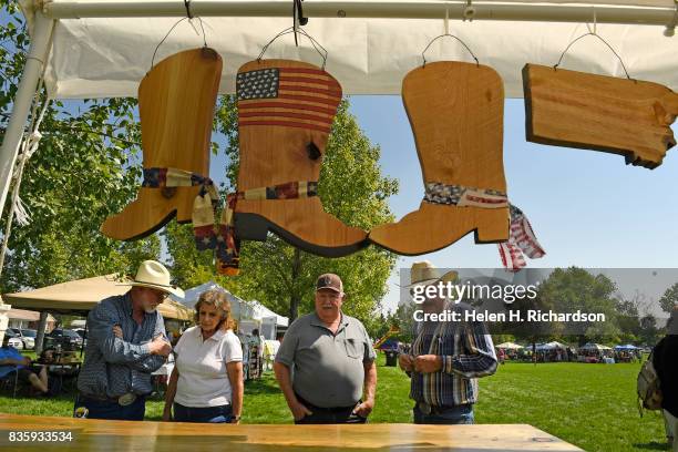 Jim Harris, left, and his brother -in-law Buster Lechner, right, owners of Bitterroot Benches, show off their wooden wares to customers at their...